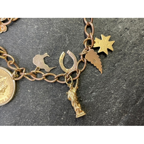 26 - Comprehensive 9ct charm bracelet, with full 1911 sovereign and various charms to include St Bernadet... 