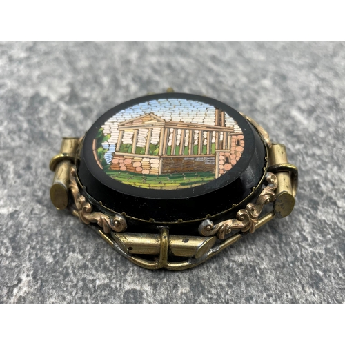 99 - A 19th century gilt metal and micro-mosaic oval brooch depicting a neo- classical colonnaded buildin... 