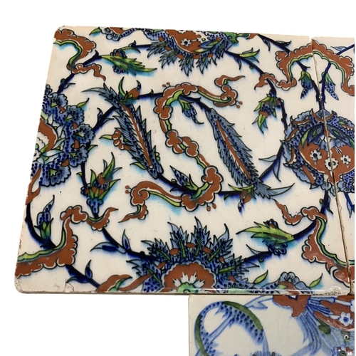 384 - Three early 20th century Iznik style polychrome pottery tiles, having chinoiserie and scrolling saz ... 