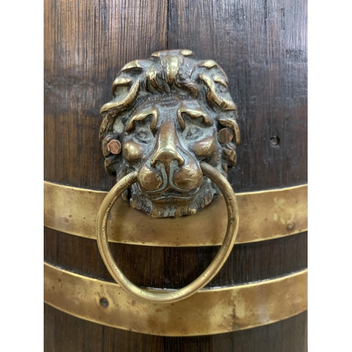 466 - Antique oak and brass bounded stick stand with twin lion head handles and fluted brass rim, H 58cm