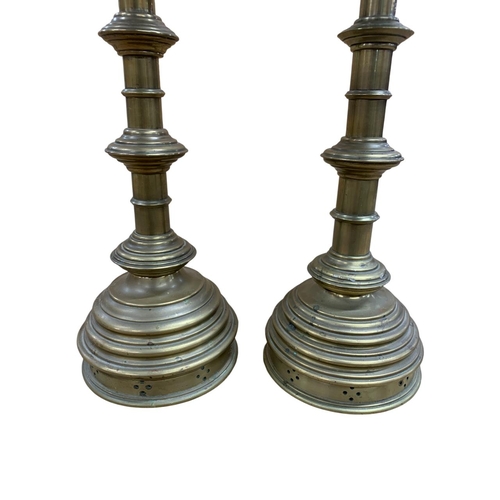 1068 - Pair of brass Ecclesiastical style alter pricket candlesticks, having stepped circular base with pie... 