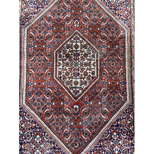 1682 - Good Persian rug with intricate handstitched detail on deep red ground, 140cm x 90cm