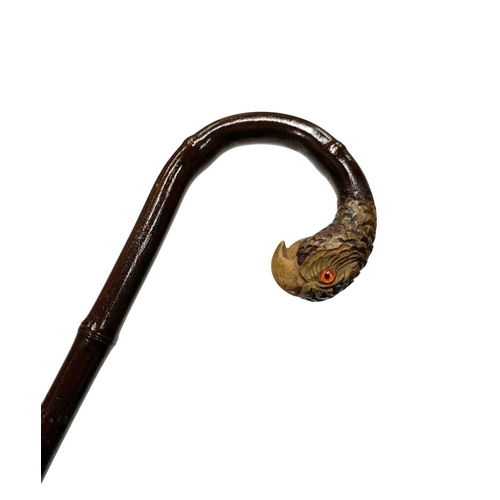 644 - Crook handled walking cane with carved parrot head terminal and inset glass eyes, having sanded down... 