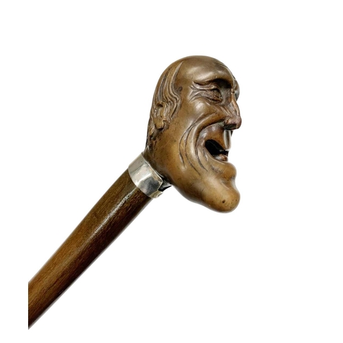 645 - Hardwood walking cane with carved laughing head handle, having a silver plated shirt-shaped collar w... 