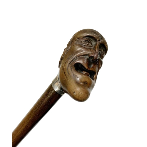 645 - Hardwood walking cane with carved laughing head handle, having a silver plated shirt-shaped collar w... 