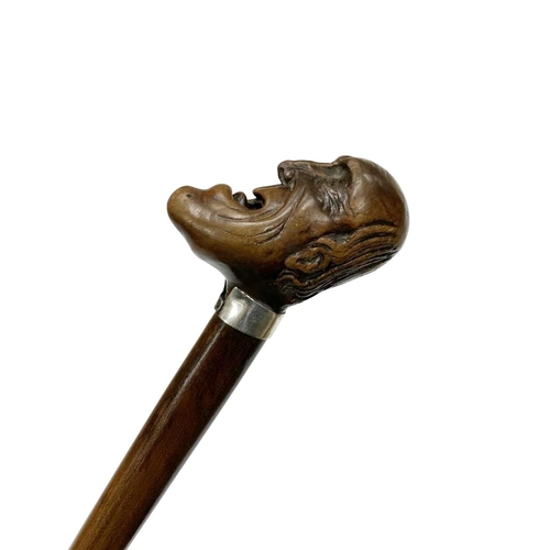 645 - Hardwood walking cane with carved laughing head handle, having a silver plated shirt-shaped collar w... 