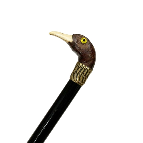 653 - Stained hardwood walking cane with wood handle carved as a birds head, having bone beak and glass in... 