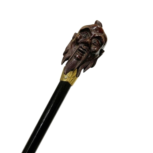 655 - Stained hardwood walking cane with hardwood handle carved as an Asian sage's head, having an 18ct go... 