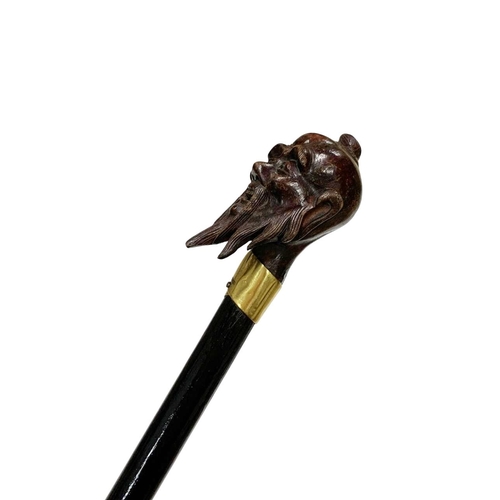 655 - Stained hardwood walking cane with hardwood handle carved as an Asian sage's head, having an 18ct go... 