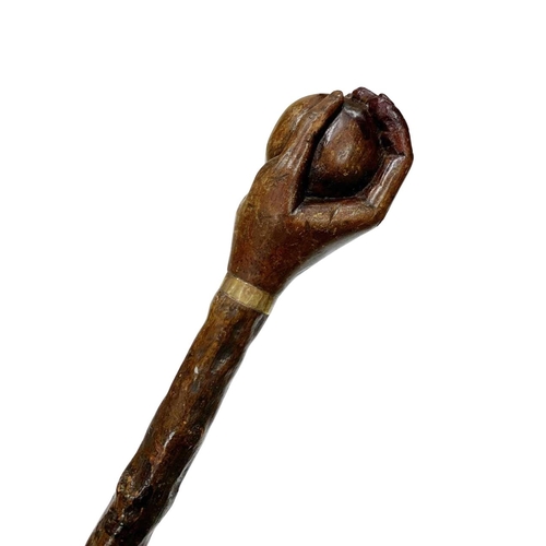 661 - Folk Art hazel wood walking cane with handle carved as a hand holding a ball, with thin metal collar... 