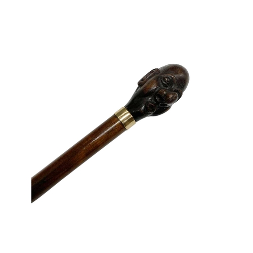 667 - Hardwood walking cane with handle carved as caricature man's head, having marked 9ct gold-plated col... 