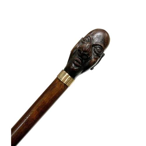 667 - Hardwood walking cane with handle carved as caricature man's head, having marked 9ct gold-plated col... 