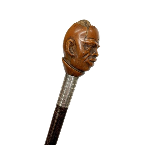 671 - Stepped partridge wood walking cane with coquilla nut-handle carved as a man's head, having silver m... 