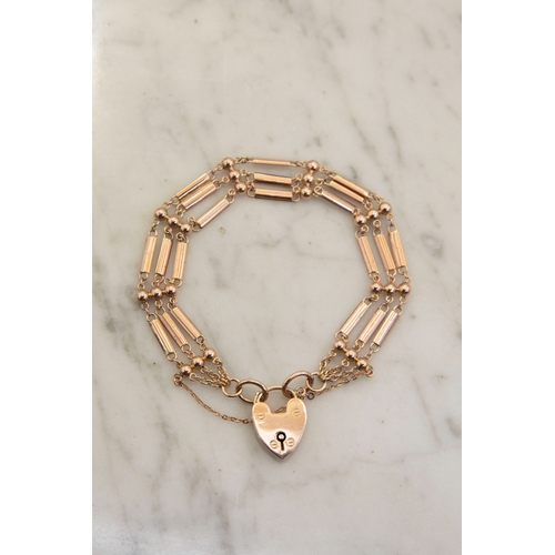 127 - An early 20th century rose gold ball and bar three-row bracelet on a heart-shaped padlock clasp stam... 