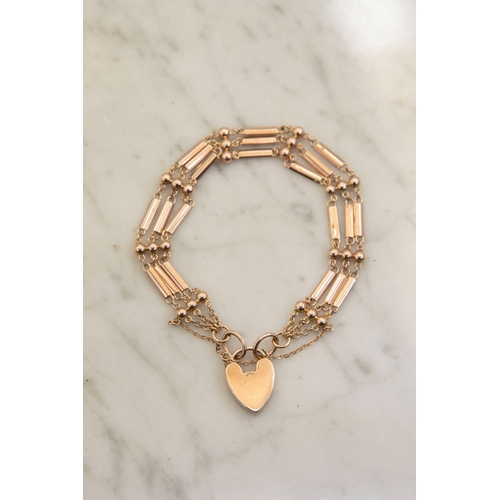 127 - An early 20th century rose gold ball and bar three-row bracelet on a heart-shaped padlock clasp stam... 