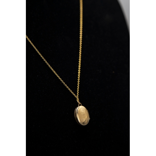 42 - A vintage 9ct gold small oval locket and chain, the locket part foliate engraved and with hallmarks ... 