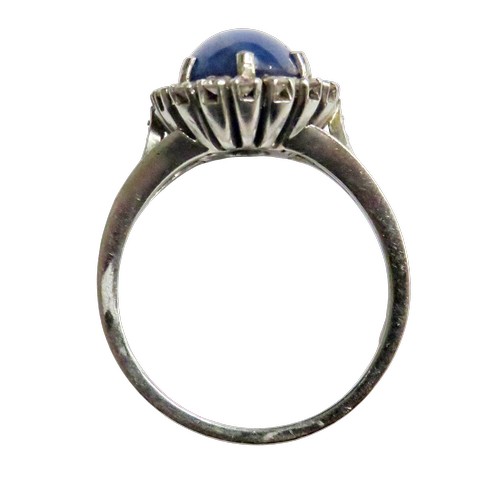 59 - A vintage platinum, 'star' sapphire and diamond oval cluster ring, the grey-ish blue oval cabochon d... 