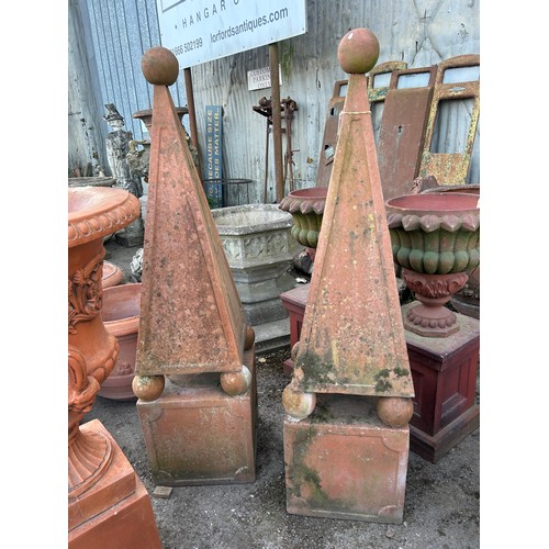 132 - Pair of terracotta obelisks with ball finials, raised on four balls and square plinths, 
Situated at... 