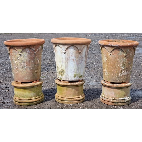 9 - Three large Italian terracotta planters with Gothic arch detail raised on circular terracotta plinth... 