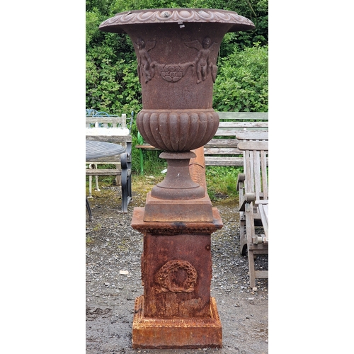 44 - Large cast iron Campana urn with lobed bowl and winged cherub relief, raised on a square cut plinth ... 