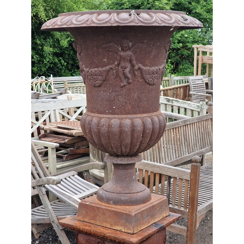 44 - Large cast iron Campana urn with lobed bowl and winged cherub relief, raised on a square cut plinth ... 