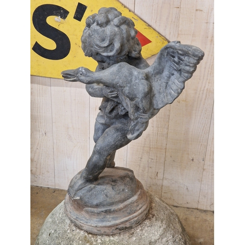 46 - Lead water feature of a boy holding a duck raised on a weathered natural stone domed plinth, H 81cm ... 