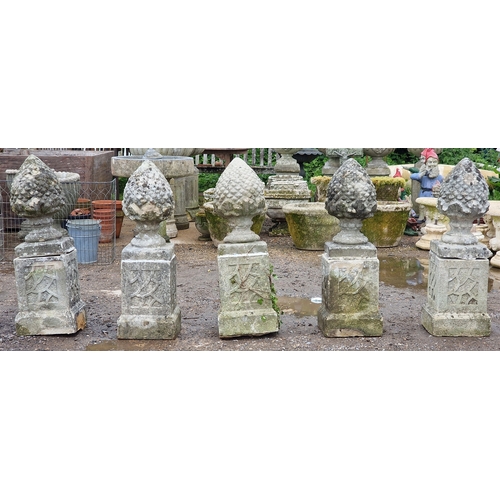 51 - Set of five weathered reconstituted stone pineapple finials raised on square cut plinths with fielde... 
