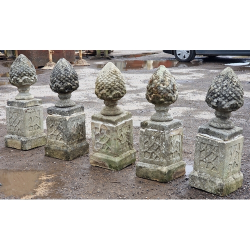 51 - Set of five weathered reconstituted stone pineapple finials raised on square cut plinths with fielde... 