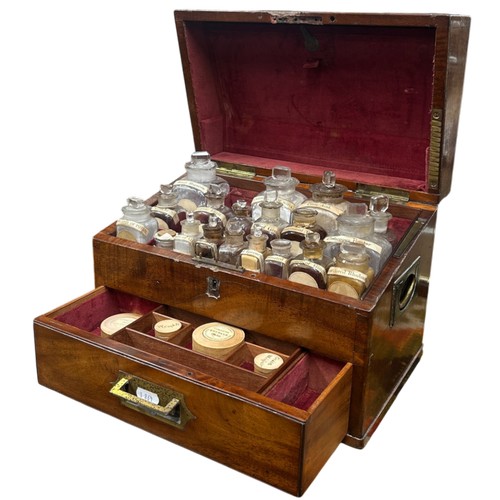 An exquisite 19th century campaign-style walnut apothecary cabinet, opening to a compartmented interior housing a wide variety of labelled apothercary bottles with contents (Citric Acid, Cretaceous Powder, Heavy Magnesia,...), with drawer below housing further chemist products (featuring Allen & Hanbury's Compound Rhubarb Pills), the cabinet with twin flush handles and further inset handle to drawer front, H 24cm x W 33cm x D 20cm