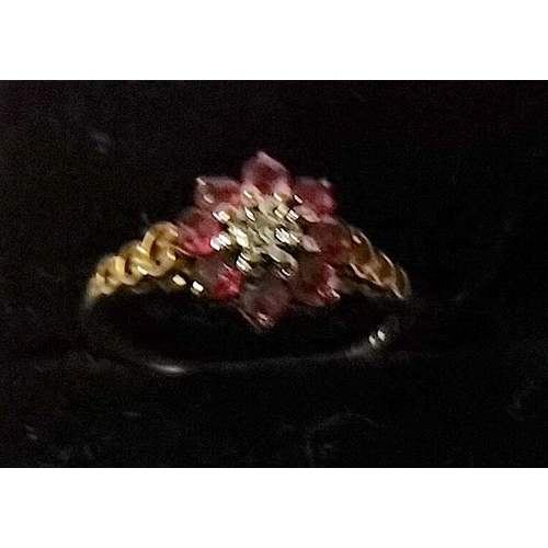 695 - 9ct gold ring 8 red stones with centre stone in white pierced shoulders size M