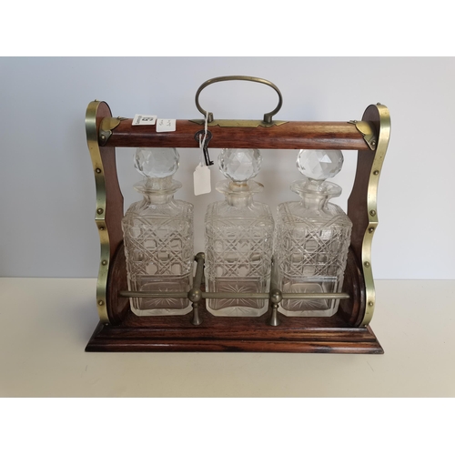 59 - Wooden Tantalus with key - brass detailing and 3 cut glass decanters