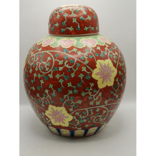 12 - A Chinese ginger jar and cover, the red ground with green foliage, blue accents, and pink and yellow... 