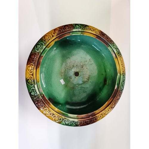 14 - A Majolica jardinière, circular, decorated in green, brown and yellow, raised on three winged zoomor... 