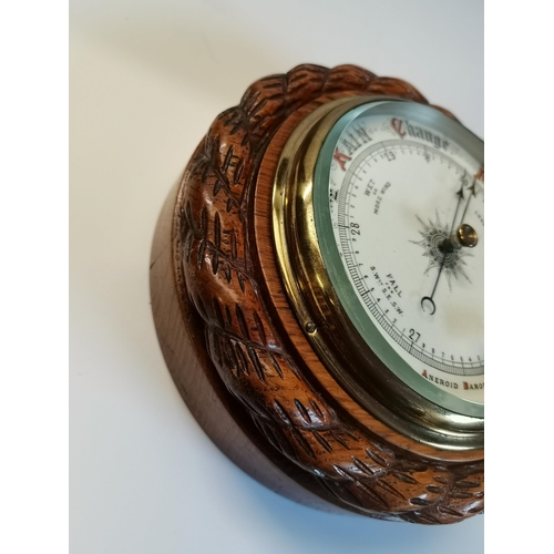 144 - An oak-mounted aneroid barometer, circular, with carved rope-twist surround, pen signature to revers... 