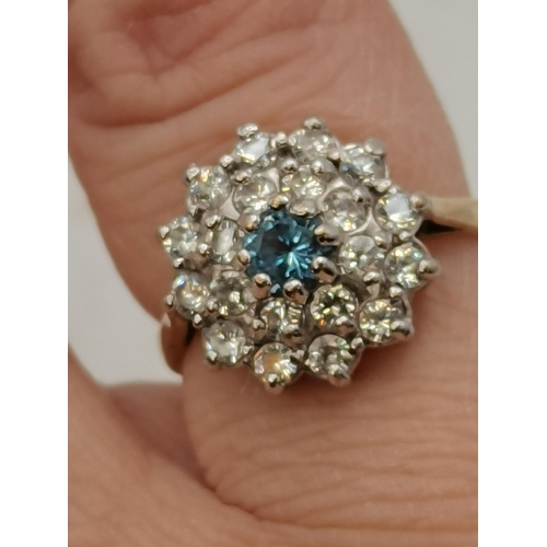 395 - A 9 carat gold cluster ring, a pale blue central stone enclosed by two circles of white stones. Ring... 