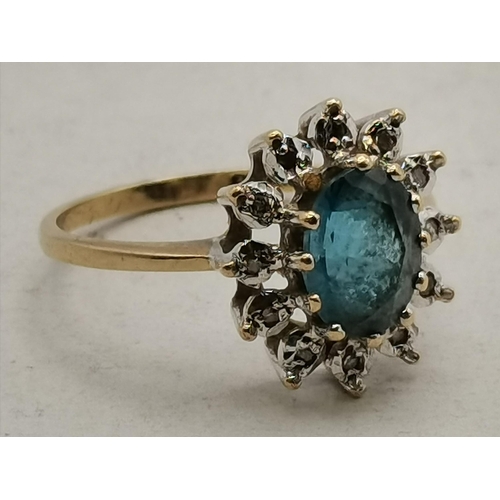 406 - Blue centre stone in claw settings surrounded by 12 white stones set in 9ct Yellow Gold Ring Stamped... 