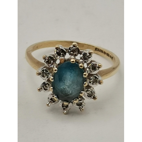 406 - Blue centre stone in claw settings surrounded by 12 white stones set in 9ct Yellow Gold Ring Stamped... 