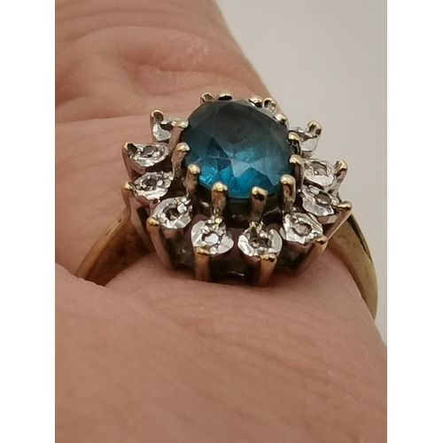 406 - Blue centre stone in claw settings surrounded by 12 white stones set in 9ct Yellow Gold Ring Stamped... 