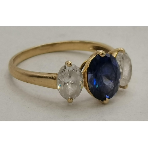 450O - A 14 carat gold three-stone ring, an oval blue topaz between two oval crystals, hallmarked, stamped ... 