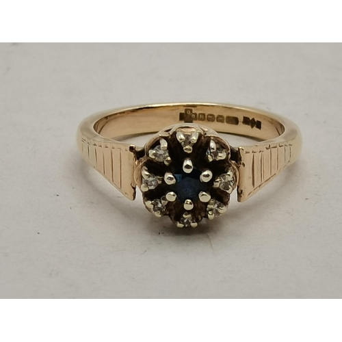 474B - A 9 carat gold cluster ring, the central blue stone surrounded by eight small white stones, in a fan... 