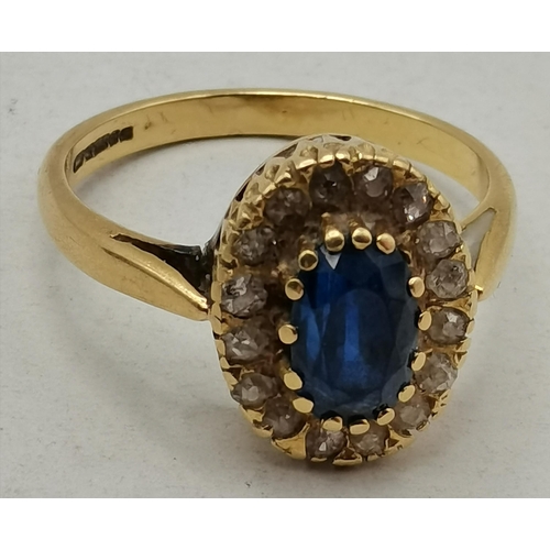 475A - An 18 carat gold sapphire and diamond cluster ring, the oval central blue stone enclosed by small wh... 