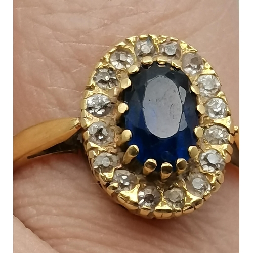 475A - An 18 carat gold sapphire and diamond cluster ring, the oval central blue stone enclosed by small wh... 