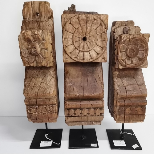 521 - Three carved Indian hardwood brackets, with flowerhead decoration, each mounted on later steel squar... 