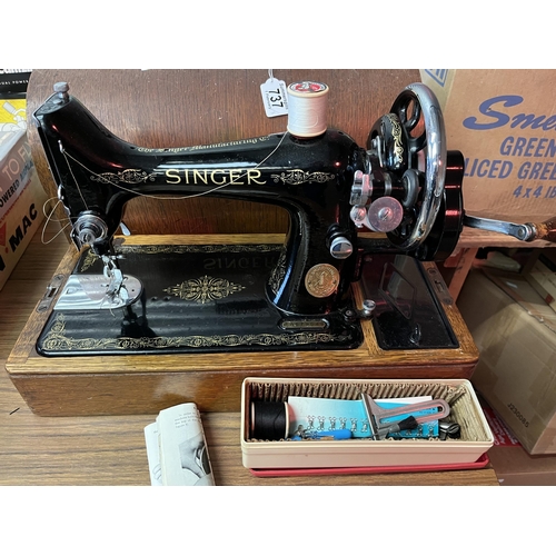 737 - A Singer sewing machine, model EA579948, black painted with gilt detailing, with wooden base and cov... 