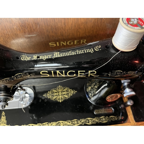 737 - A Singer sewing machine, model EA579948, black painted with gilt detailing, with wooden base and cov... 