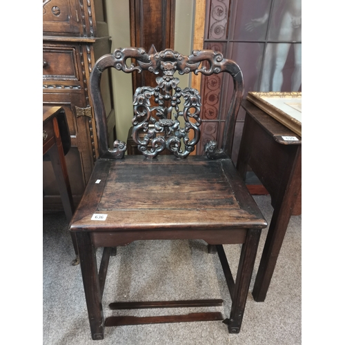 636 - A Chinese heavily carved hall chair with flower and devil style decoration