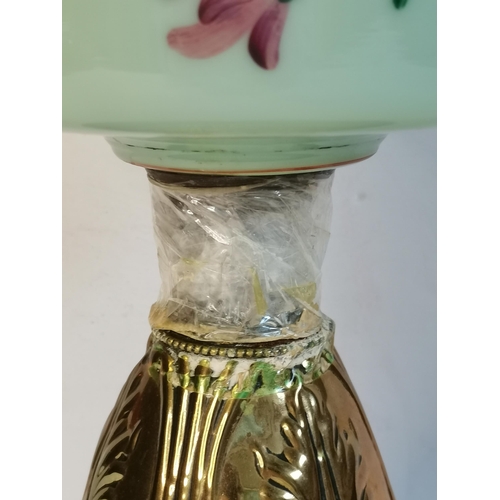 11 - A Victorian glass oil lamp, the floral enamel painted pale green glass reservoir raised on a spreadi... 