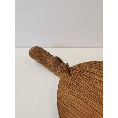 200D - Robert Thompson, a Mouseman oak cheese board, of typical form, lightly adzed, with carved mouse sign... 