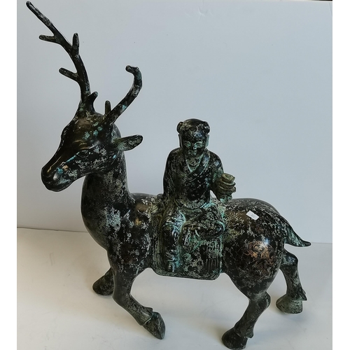 37 - A Chinese bronzed metal sculpture of a figure riding a deer, the stag with gilded script character m... 