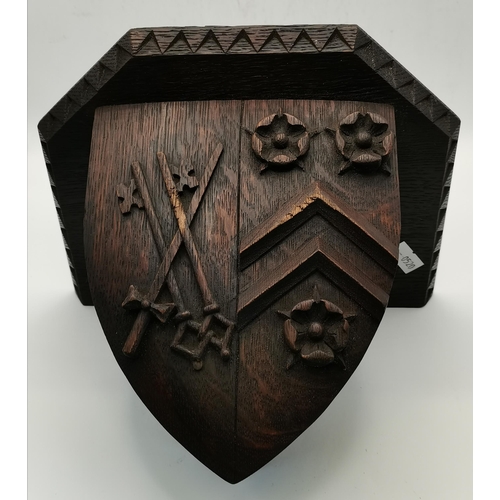 83 - A wooden wall bracket as a shield carved with a crest; together with a carved figure of a bishop. (2... 